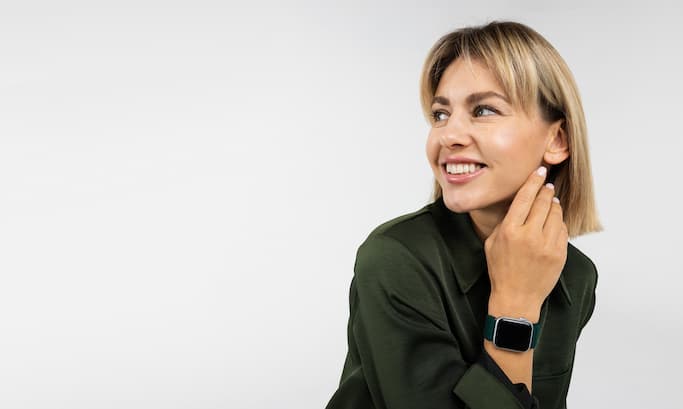 Smiling person wearing a smartwatch, looking to the side.